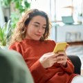 Woman looking at a smart phone while sitting on a lounge.